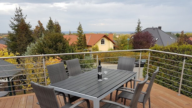Eine Terrasse mit Tisch und Stühlen mit Blick auf eine Wohngegend mit Häusern und Bäumen.
