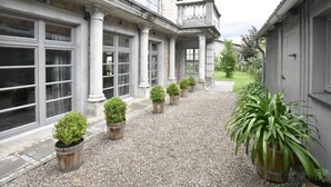 A building with a gravel pathway lined with potted plants, large windows, and a brick facade. - Apartment in Detershagen With Terrace (Kroepelin)