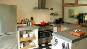 Una cucina moderna con cappa in acciaio inossidabile, forno integrato e lavello. Si notano ripiani con stoviglie e un tagliere sul piano di lavoro.
