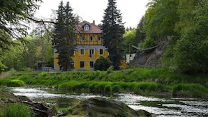 A yellow building with a red roof, surrounded by greenery and a river. - Exclusive Apartment in an art Nouveau Villa (Grossschirma)