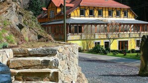 Une maison traditionnelle à colombages, avec un toit en pente, des marches en pierre menant à l’entrée et une allée gravillonnée.
