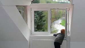 Une pièce avec un plafond en pente et une fenêtre donnant sur une rivière.