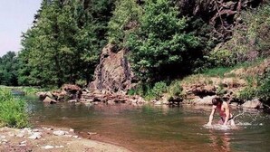 Un paysage naturel comprenant une rivière, un terrain rocheux et une forêt dense.