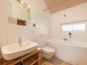 A modern bathroom with a freestanding sink, a toilet, and a bathtub. - Bungalow by the Sea With Sauna in Germany (Sierksdorf)
