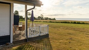 Un espace extérieur abrité, aménagé pour s’asseoir, avec vue sur la mer.