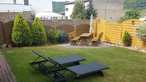 A backyard with two black lounge chairs, a wooden fence, and a yellow gate. - Modern Holiday Apartment With Large Garden Near the River Moselle (Neumagen-Dhron)