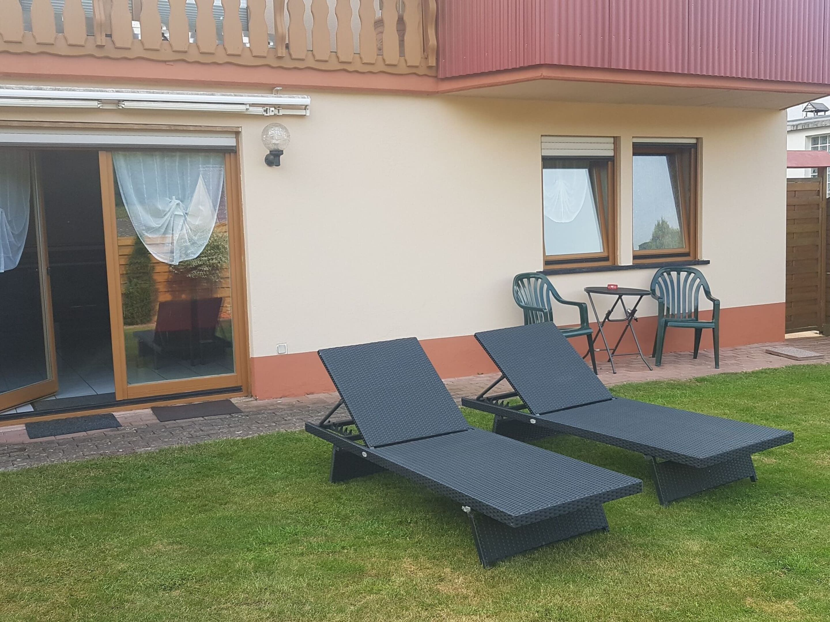 Un patio con dos sillones, una mesa y dos sillas.