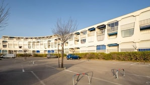 A parking lot with a modern building in the background. - La Croisière by Interhome (Port Camargue)