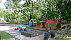 Ein Spielplatz mit verschiedenen Spielgeräten, einem Picknicktisch und einer Blockhütte.