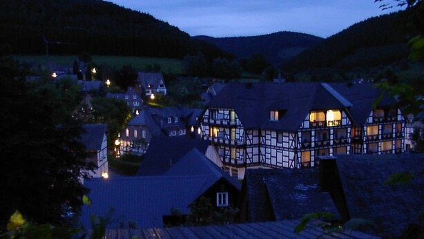 A traditional European village at dusk with timber-framed houses and a small church.