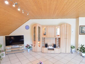 Relax in this stylish living room with a flat-screen TV, entertainment unit, and a potted plant.