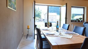 A dining room with a wooden table set for four, a view of the outside, and a window with a view of the countryside.