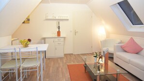 Un apartamento moderno con comedor, kitchenette y sala de estar con sofá y mesa de centro de vidrio.