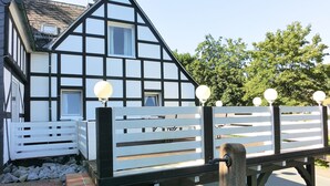 Une maison traditionnelle à colombages, avec une clôture blanche et des luminaires sphériques.