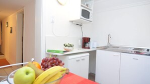 Una cocina moderna con armarios blancos, un microondas y una cafetera. Hay un cuenco de fruta en la encimera.