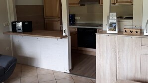 Una cocina compacta con armarios de madera, microondas integrado y lavavajillas.
