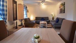 A modern living room with a wooden dining table, two sofas, a coffee table, and a lamp.