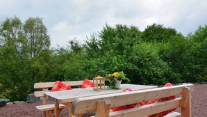 A wooden picnic table with benches, a lantern, and a potted plant with yellow flowers.