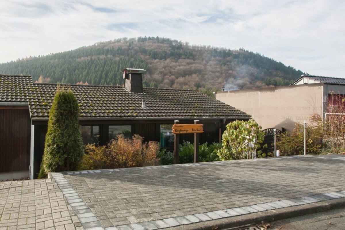 A building with a tiled roof, a signboard, and a view of a forested hill.
