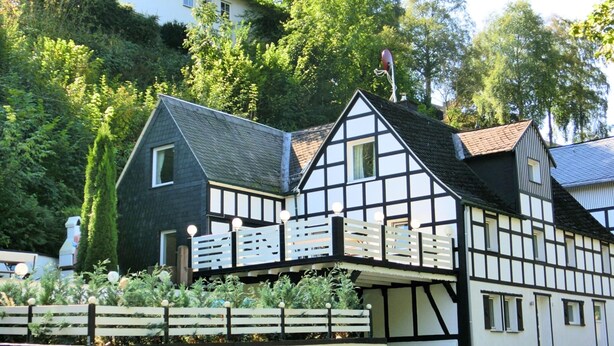 A traditional half-timbered house with a sloped roof, a visible chimney, and a small balcony with lights. - Gruppenferienhaus im Sauerland (Schmallenberg)