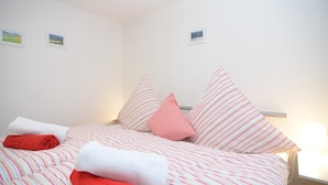 A neatly made bed with striped bedding, pillows, and rolled towels. - Gruppenferienhaus im Sauerland (Schmallenberg)