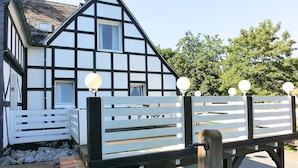 A traditional half-timbered house with a white fence and spherical light fixtures. - Gruppenferienhaus im Sauerland (Schmallenberg)