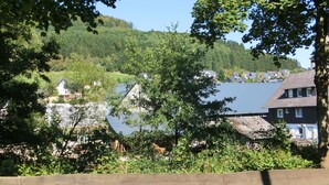 A residential area with houses, a lake, and a forested hill in the background. - Gruppenferienhaus im Sauerland (Schmallenberg)