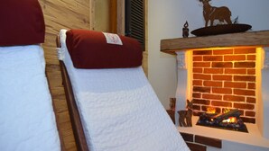 Um quarto com uma cama, lareira e parede de madeira.