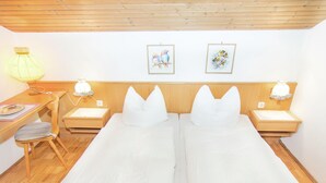 A double room with two beds, a desk, a chair, and two bedside lamps.