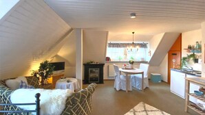 A cozy attic living space with a sofa, a dining table, and a kitchen area. - Holiday Home With Garden in Weissenbrunn (Weissenbrunn)