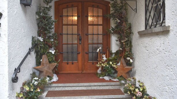 A wooden double door with glass panels, flanked by decorative greenery and star-shaped ornaments. - Holiday Home With Garden in Weissenbrunn (Weissenbrunn)