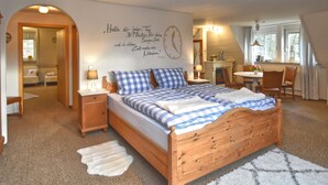 A cozy bedroom with a wooden bed, a wall clock, and a cozy fireplace. - Holiday Home With Garden in Weissenbrunn (Weissenbrunn)