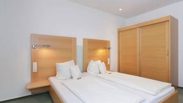 A double bed with a wooden headboard and nightstands, a wardrobe, and a wall-mounted light fixture.