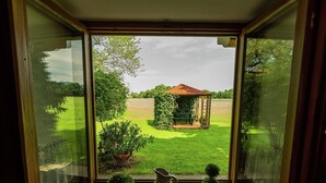 Una ventana con vistas a un jardín, un pabellón y un estanque.
