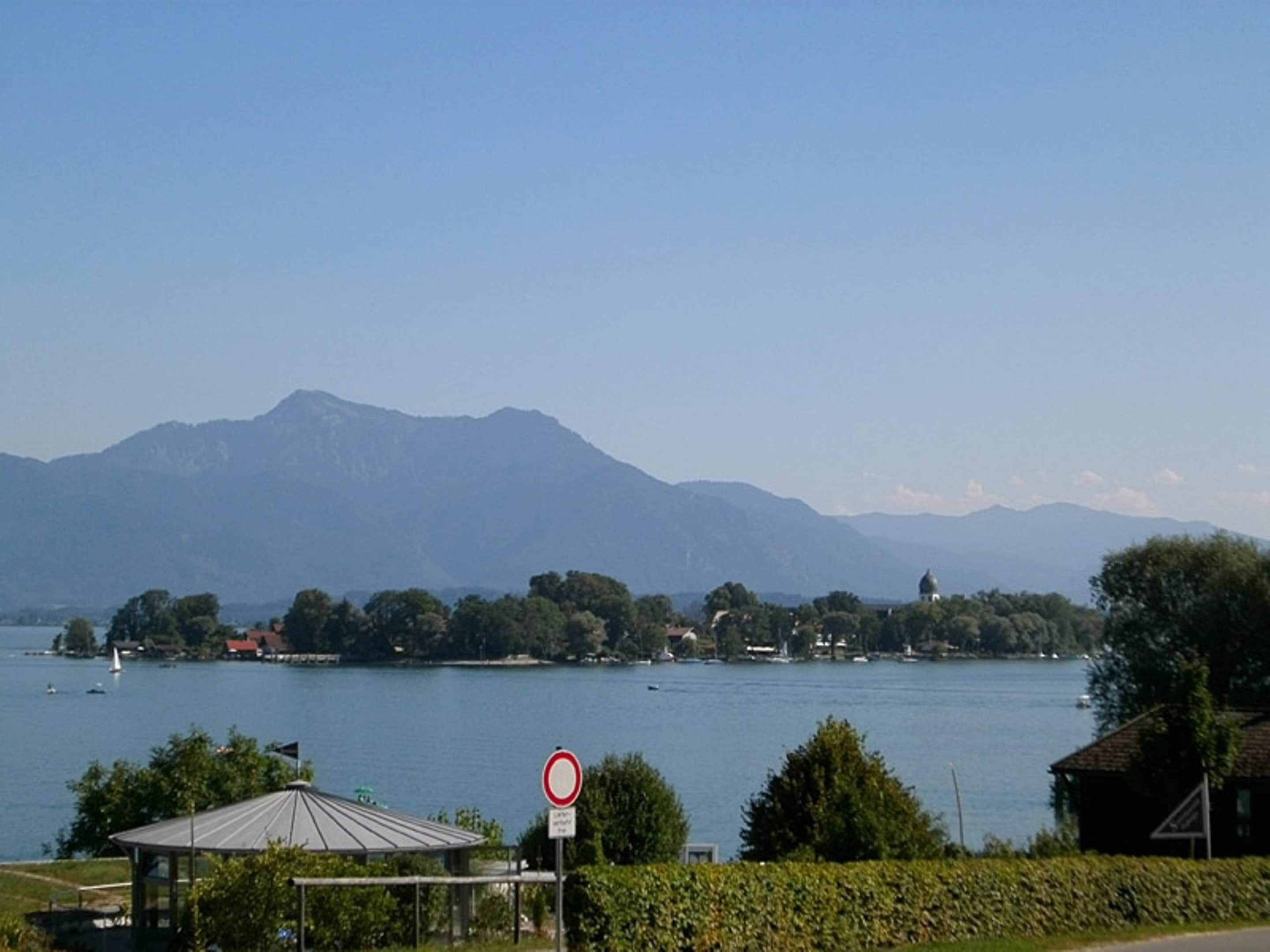 A lakeside view with mountains in the background, a gazebo, and a no parking sign.