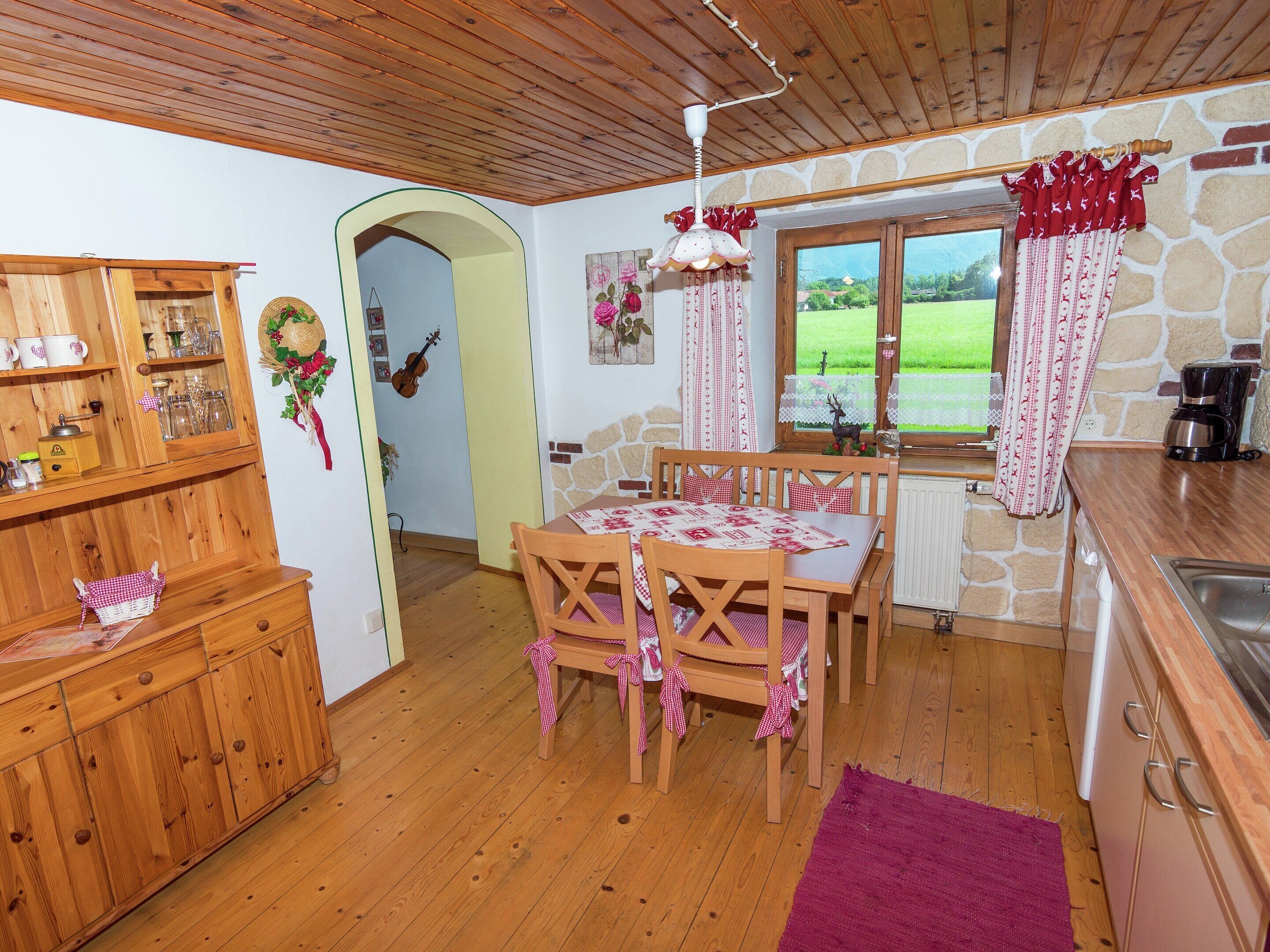 Eine gemütliche Küche mit Holzausstattung, einem Esstisch mit kariertem Tischläufer und einer Steinwand.