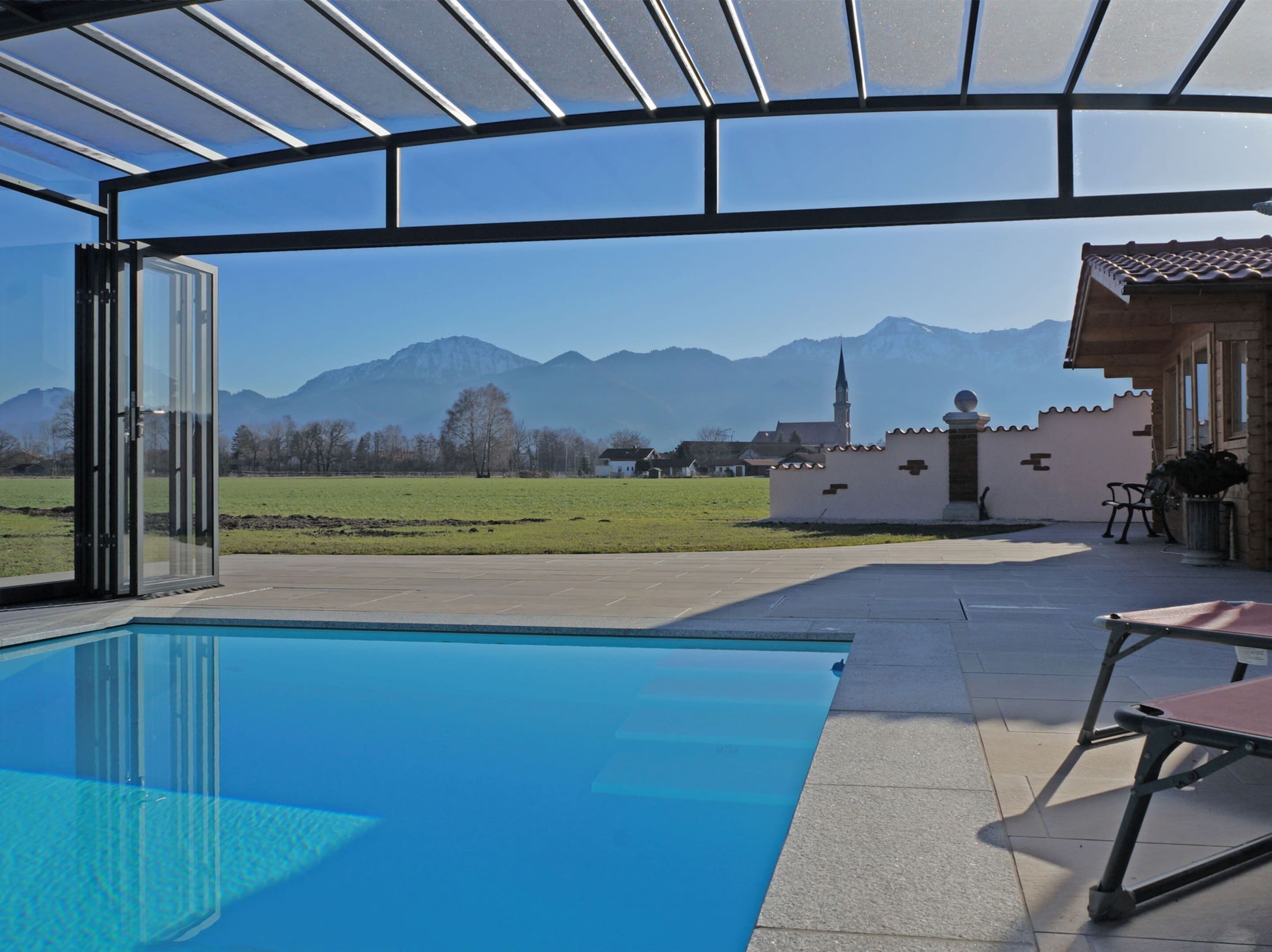 Ein Pool im Freien mit freiem Blick auf Berge und einer Kirche im Hintergrund.
