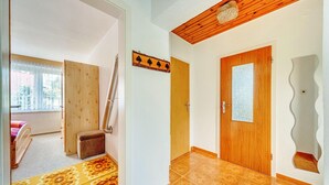 Una habitación con puerta de madera, alfombra estampada y ventana con cortinas.