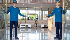 A hotel lobby with a modern design, featuring a reception desk, seating area, and a glass partition. - Calix Hotel (Da Nang)