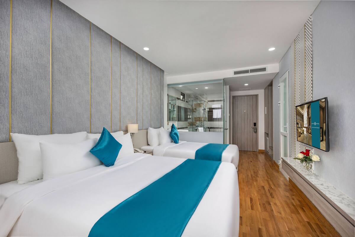 A hotel room with two beds, a large mirror, and a TV on the wall.