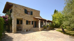 Une maison en pierre dotée d’un porche abrité, d’un chemin en pierre et d’une végétation luxuriante.