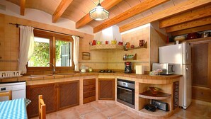 Une cuisine de taille réduite, dotée de meubles de rangement en bois, d’un four encastré et d’un réfrigérateur.