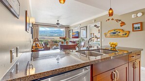 A modern kitchen with a large island, stainless steel appliances, and a view of mountains.