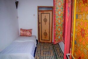 A bedroom with a bed, a door, and a patterned floor.
