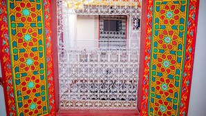 A window with intricate metalwork and colorful patterns on the surrounding walls. - La casa dar Rayan  (Fes)