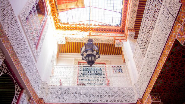 A multi-level interior with ornate white lattice work and colorful tile patterns. - La casa dar Rayan  (Fes)