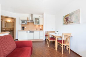 A compact living space with a kitchenette, a dining area, and a red sofa.