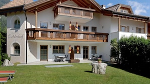 A two-story building with a balcony, outdoor seating, and a well-maintained lawn. - Cosy Holiday Apartment "Tischlerhof - Typ C" with Wi-Fi and Mountain View (Dorf Tirol bei Meran)