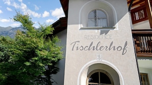 A building with a sign reading 'RESIDENCE Tischlerhof' and a window with a view of mountains. - Cosy Holiday Apartment "Tischlerhof - Typ C" with Wi-Fi and Mountain View (Dorf Tirol bei Meran)