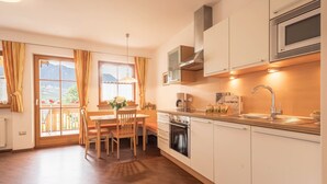 A modern kitchen with a dining area, wooden flooring, and a view through the window. - Holiday Apartment "Tischlerhof - Typ B" with Wi-Fi, Terrace and Mountain View (Dorf Tirol bei Meran)
